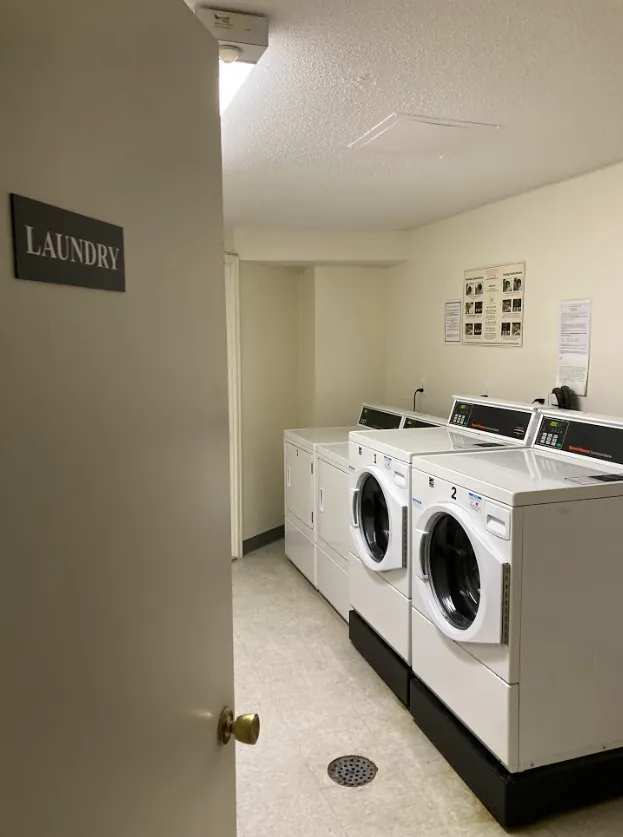 Shared laundry room with washers and dryers, seen through a door marked Laundry