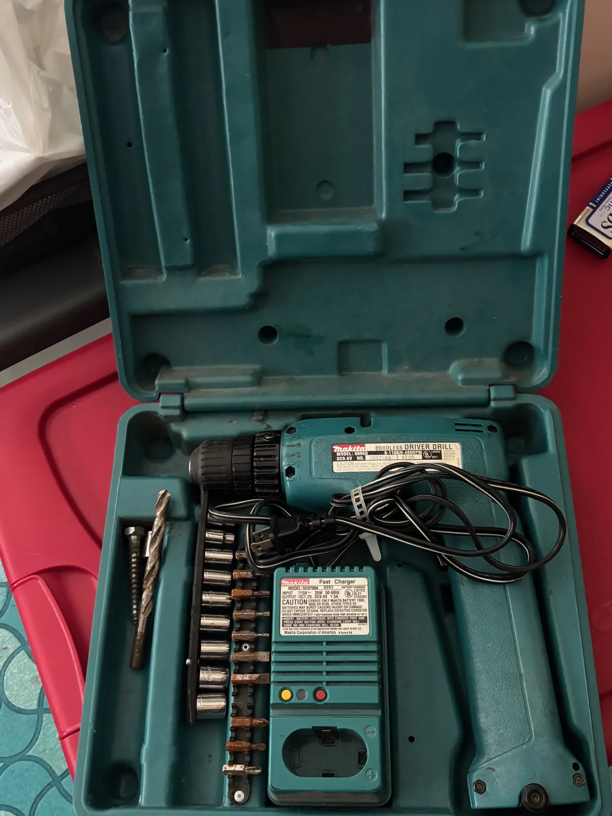 Open case with a cordless drill, charger and bits